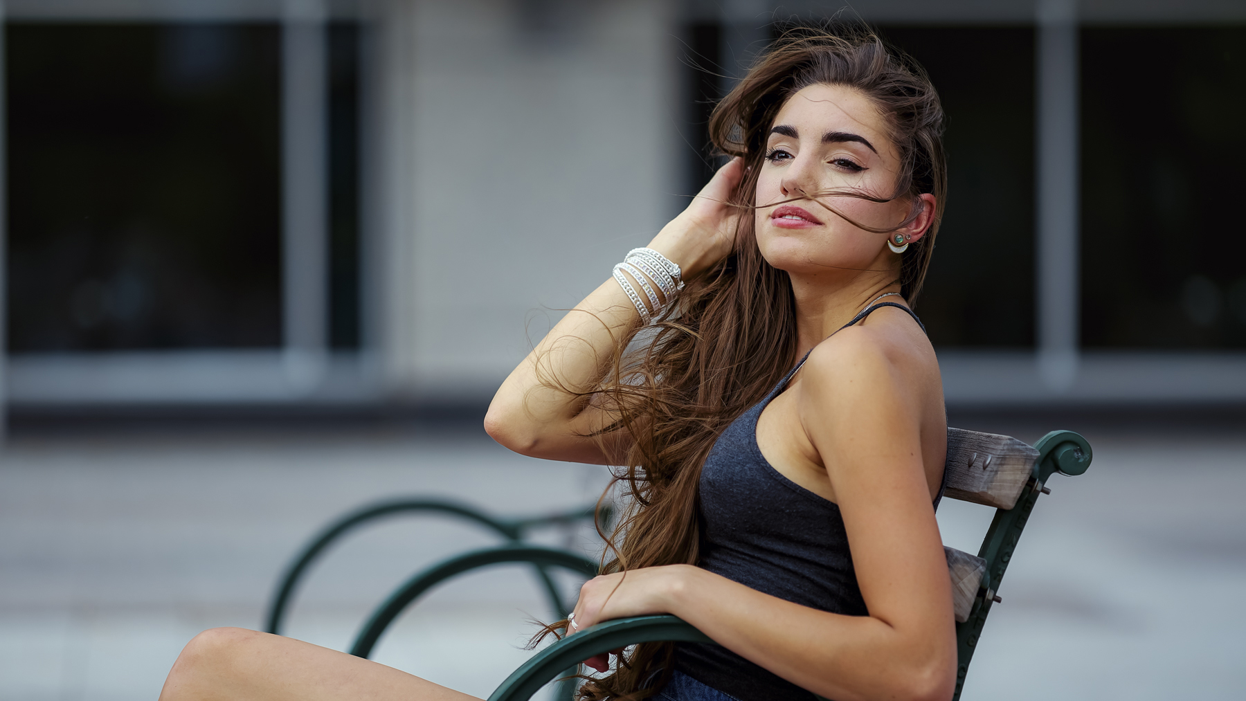 A woman with windblown hair sitting on a bench, captured by Rex Jones, showcasing casual portrait photography in Utah